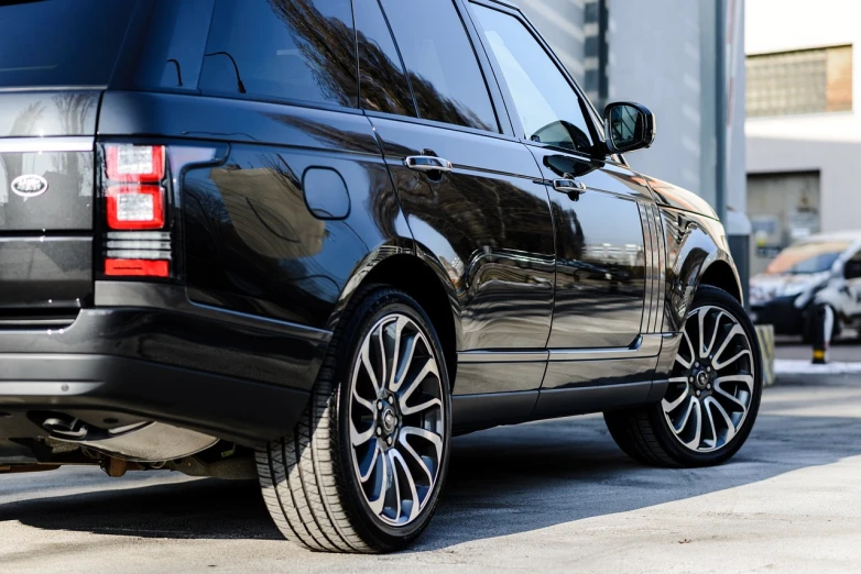 a black range rover parked in front of a building, a picture, by Thomas Häfner, unsplash, realism, highly detailed wheels, side view close up of a gaunt, highly polished, 2 0 1 4