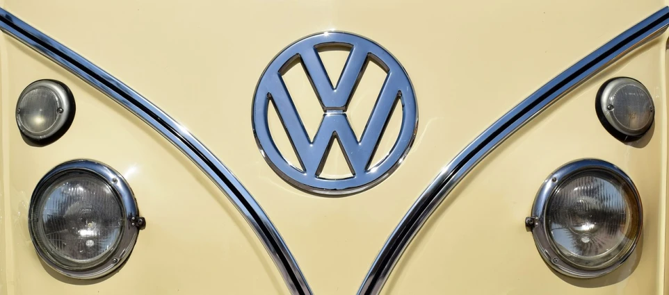 a close up of the front of a yellow vw bus, 2 d logo, wikimedia, sharp metal crest, cream