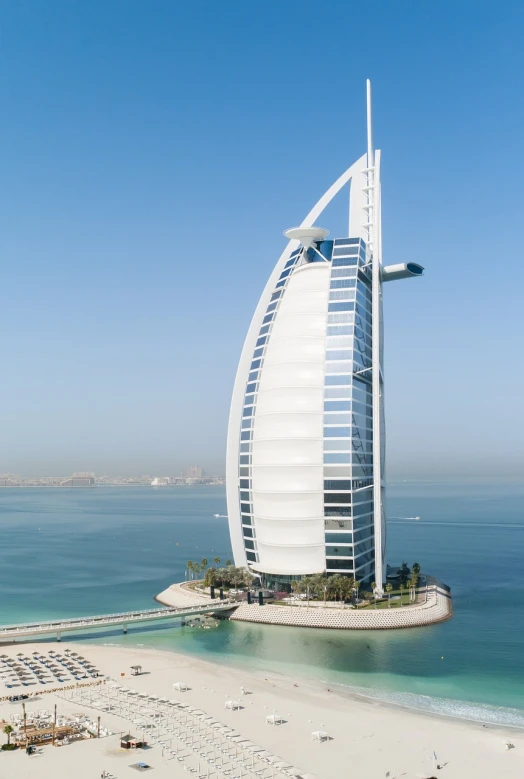 a tall building sitting on top of a sandy beach, a stock photo, by Edmund Greacen, shutterstock, hurufiyya, sheik mohammad ruler of dubai, nautilus, sails, hotel