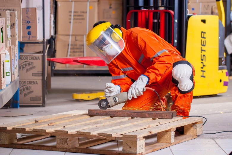 a man in an orange coverall working on a piece of wood, a stock photo, by Bernardino Mei, shutterstock, pallet, usa-sep 20, corporate photo, maintenance area