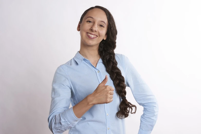 a woman in a blue shirt giving a thumbs up, a stock photo, inspired by Christen Dalsgaard, long braided black hair, magda torres gurza, young business woman, half - length photo