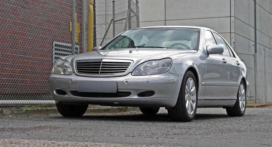 a silver car parked in front of a building, pixabay, photorealism, with a white muzzle, mercedez benz, shot on a 2 0 0 3 camera, fully armoured