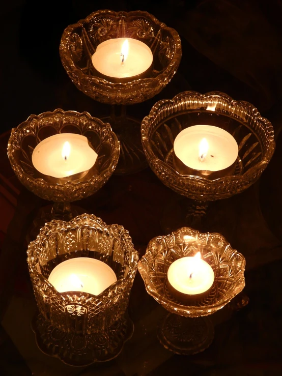 a group of lit candles sitting on top of a table, a still life, by Brenda Chamberlain, flickr, bowl, crystal lights, close - ups, floating