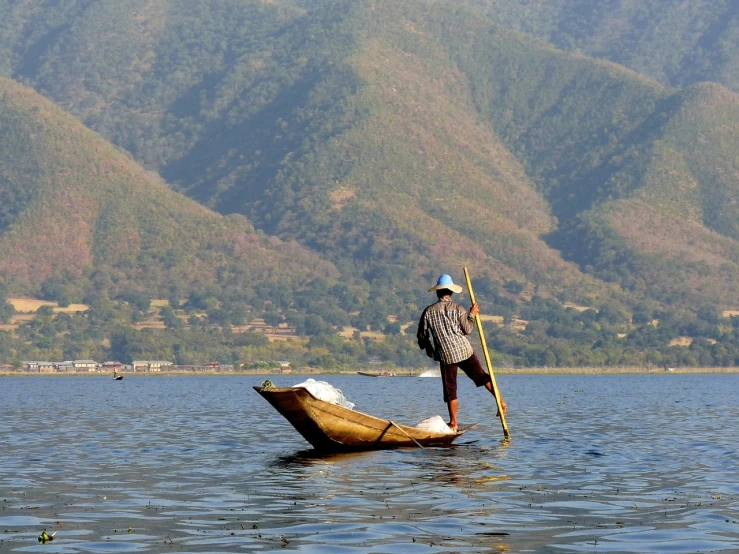 a man on a boat in the middle of a lake, by Robert Brackman, flickr, mingei, with mountains in background, working hard, cane, full res