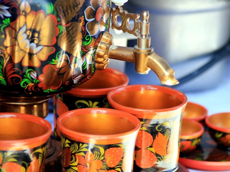 a group of cups sitting on top of a table, by Miroslava Sviridova, shutterstock, folk art, taps with running water, closeup - view, lacquerware, trailer