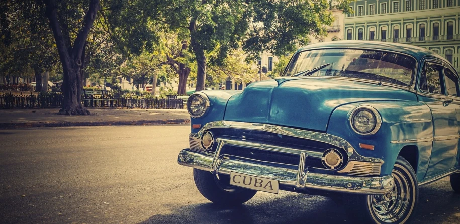 an old blue car parked on the side of the road, a photo, by Alexander Robertson, pexels, photorealism, cuban revolution, photorealism. trending on flickr, retro effect, close up portrait photo