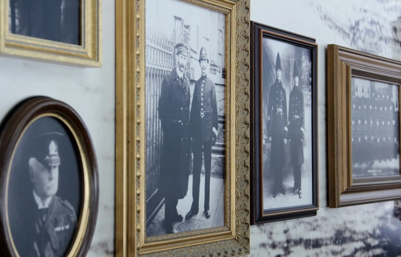 a number of framed pictures on a wall, by Gen Paul, police officers, victorian era, closeup shot, ancestors