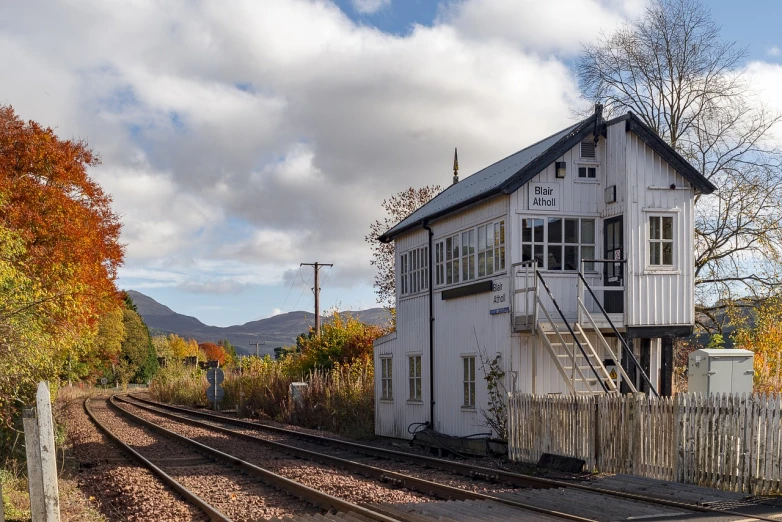 a white building sitting on the side of a train track, by Roar Kjernstad, black mountains, october, panoramic, platform 9 3 / 4