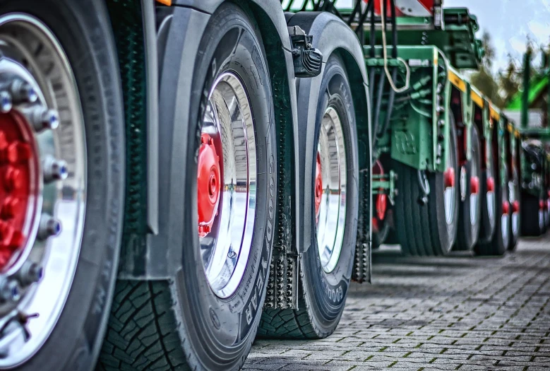 a row of semi trucks parked next to each other, a photo, by Thomas Häfner, pixabay, photorealism, highly detailed wheels, close-up shot from behind, big!!!!!!!!!!!!, tyre mark