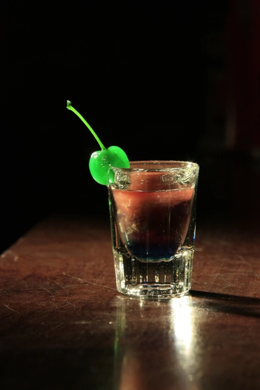 a close up of a drink in a glass on a table, flickr, cherry explosion, purple and green, cowboy shot, dark rainbow