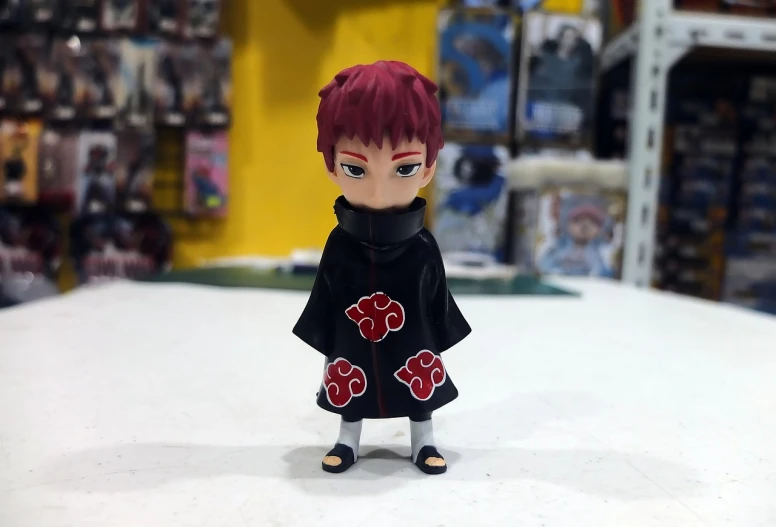 a close up of a toy on a table, inspired by Munakata Shikō, shin hanga, crimson red hair and red eyes, full body black and red longcoat, little kid, naruto