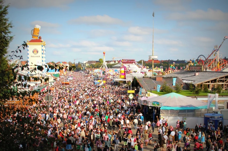 a large crowd of people at a carnival, a photo, by Werner Gutzeit, shutterstock, happening, drone wide shot, octoberfest, wide shot!!!!!!, “wide shot