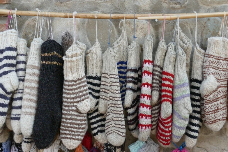 a bunch of socks hanging on a clothes line, by Etienne Delessert, folk art, sheep wool, quechua, striped socks, hut