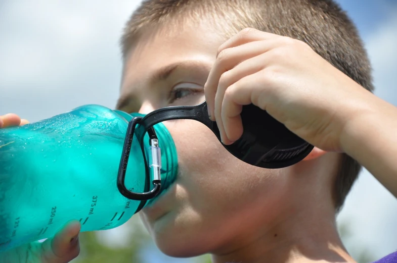 a young boy drinking from a water bottle, by Jan Rustem, pixabay, implanted sunglasses, side profile shot, photograph credit: ap, detail