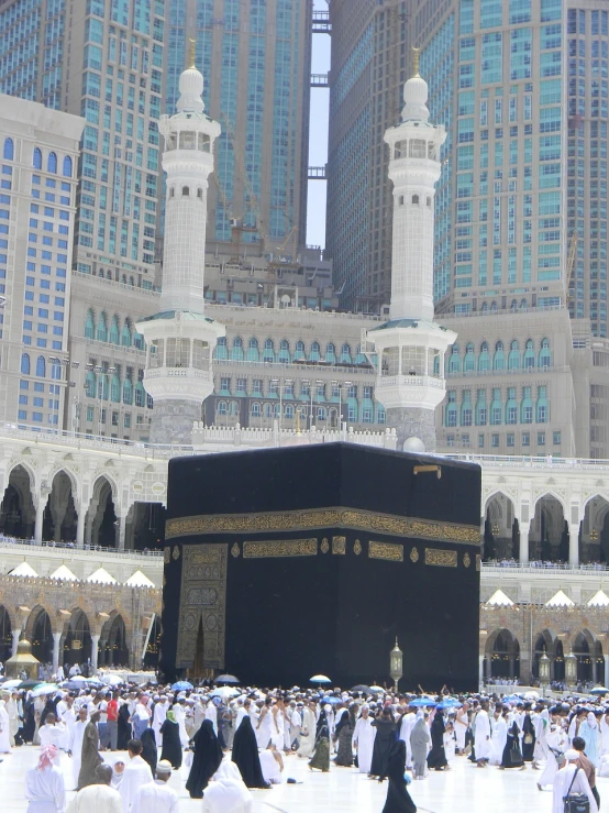 a group of people standing in front of a building, a picture, by Sheikh Hamdullah, pexels, hurufiyya, the masjid al-haram in mecca, viewed from the ground, tomb, buildings covered in black tar