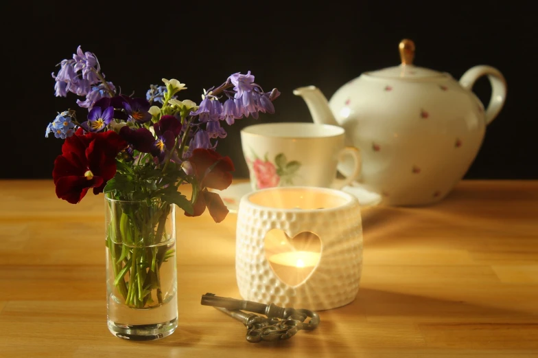 a vase filled with flowers next to a teapot, flickr, natural candle lighting, back - lit, miniature product photo, homely atmosphere