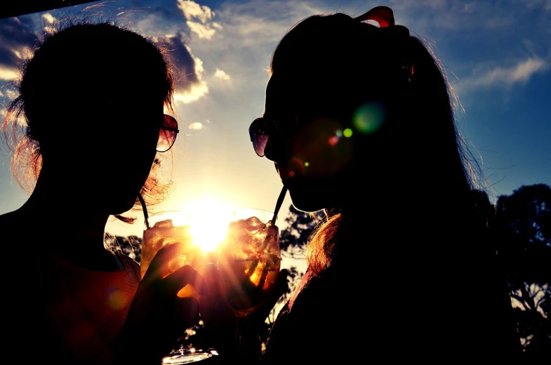 a couple of women standing next to each other, by Jan Rustem, pexels, romanticism, refracted sunset, drinking and smoking, summer sun, silhouette :7