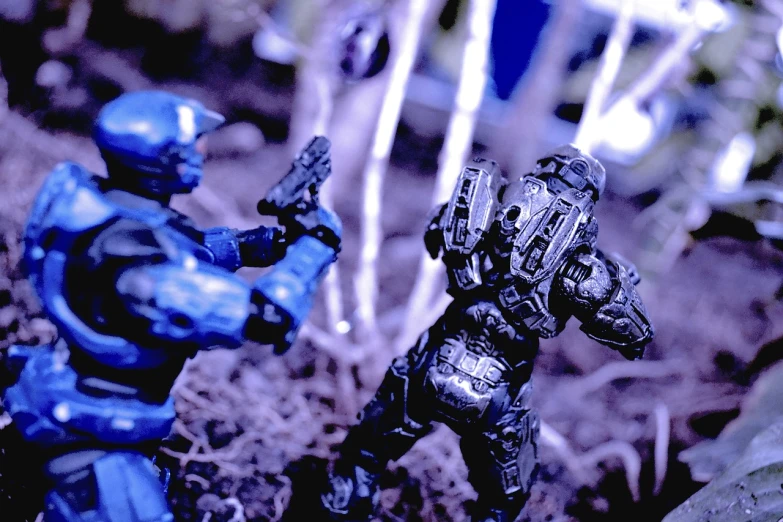 a couple of action figures standing next to each other, a macro photograph, flickr, holography, halo 3, high contrast!, on a battle field, 🕹️ 😎 🔫 🤖 🚬