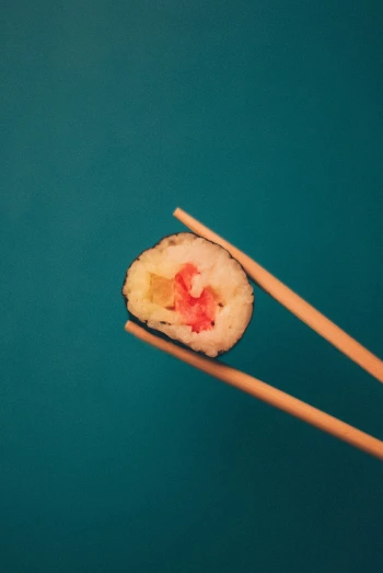 a pair of chopsticks holding a piece of sushi, unsplash, with a blue background, red-eyed, rinko kawauchi, uncomfortable