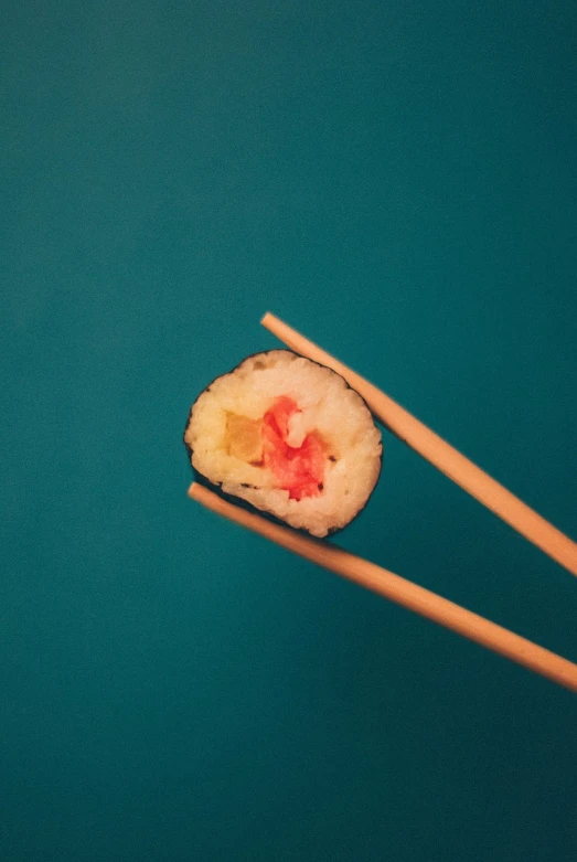 a pair of chopsticks holding a piece of sushi, unsplash, with a blue background, red-eyed, rinko kawauchi, uncomfortable