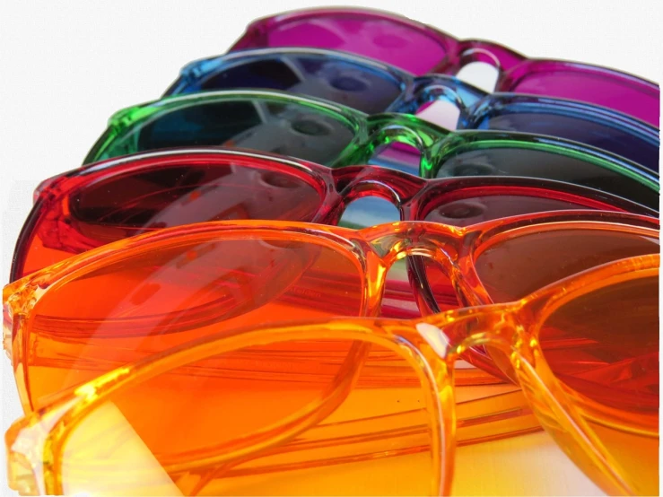 a group of colorful sunglasses sitting on top of each other, a picture, plasticien, translucent glass shine, istockphoto, deep colour\'s, vibrant light color scheme