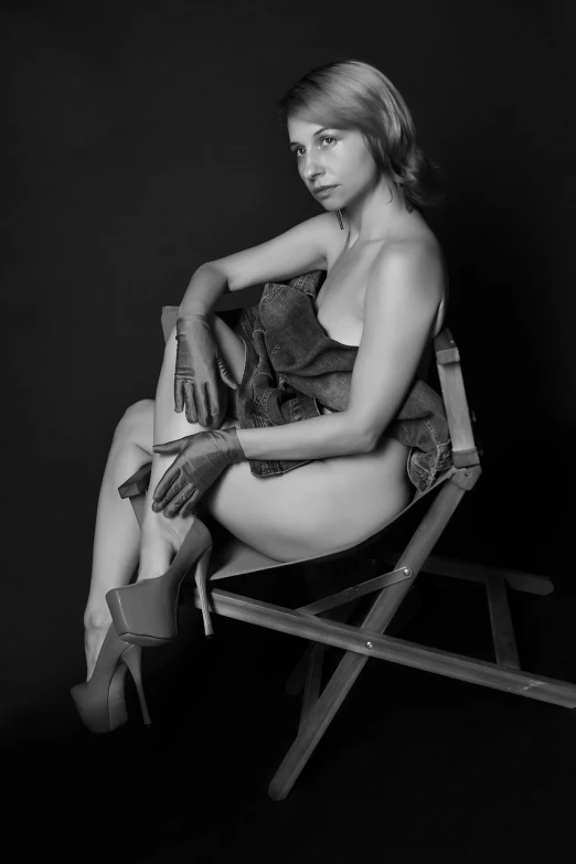 a black and white photo of a woman sitting in a chair, inspired by Yousuf Karsh, photorealism, high heels and gloves. motion, 4 k editorial photograph, wrapped in leather straps, candid portrait photo