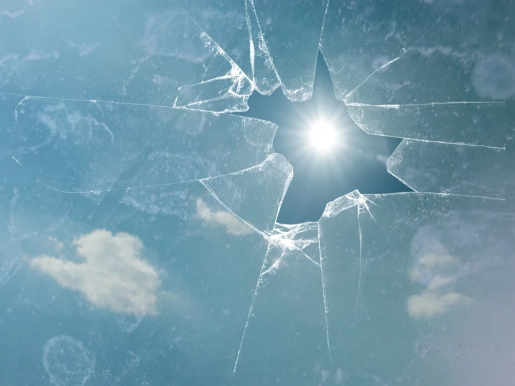 a broken glass window with the sun shining through it, a picture, conceptual art, sunny sky background, istockphoto, bullet holes, star in the sky