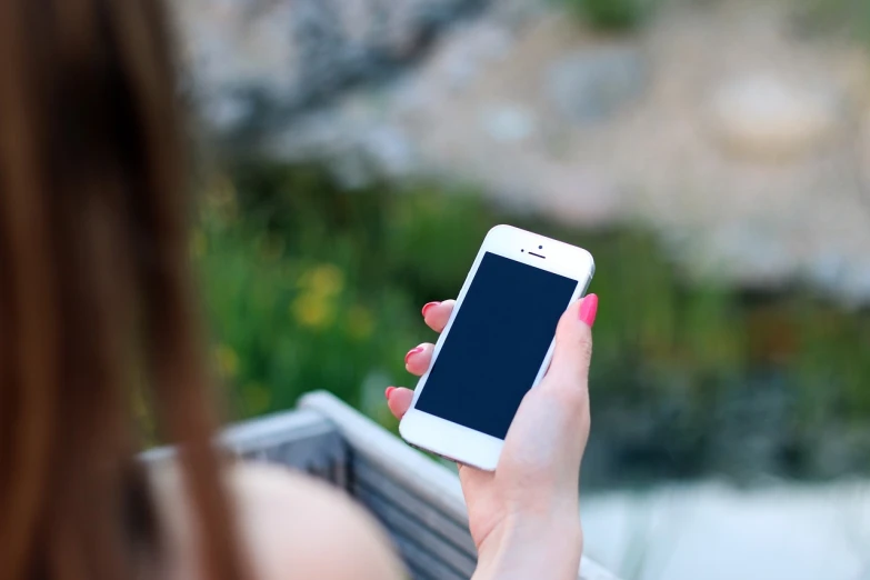 a close up of a person holding a cell phone, a picture, happening, sitting in the garden, iphone 15 background, girl, full res