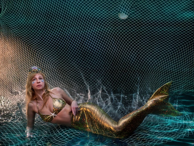 a woman in a mermaid tail swims in the water, net art, posing in leotard and tiara, draped in gold, wearing fishnets, marbella