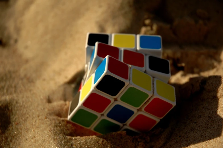 a rubik cube sitting on top of a sandy beach, a picture, cubo-futurism, color blocks, innocent mood, close - ups, islamic