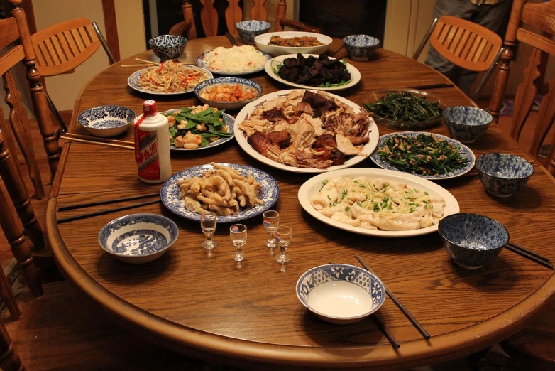 a wooden table topped with plates of food, by Wen Boren, flickr, holiday, chinese, family dinner, chicken