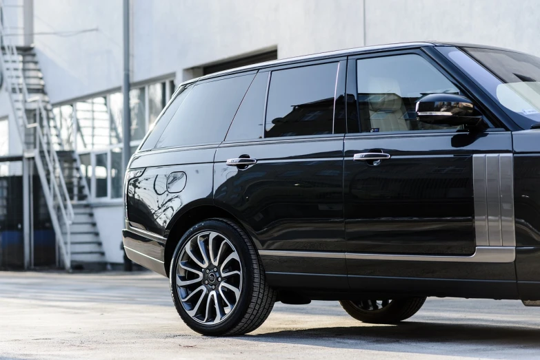 a black range rover parked in front of a building, a picture, by Thomas Häfner, side view close up of a gaunt, detailed wheels, high resolution, extremely polished