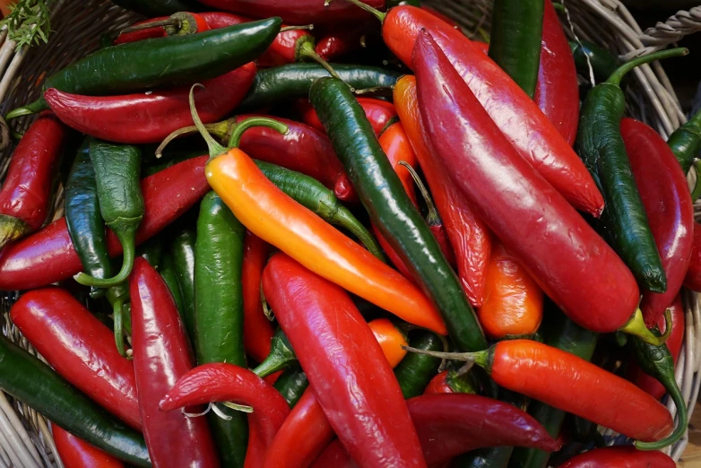 a basket filled with lots of red and green peppers, with a pointed chin, warm coloured, paisley, flames