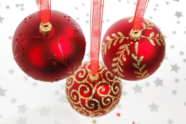 three red christmas ornaments hanging from a red ribbon, a photo, many stars, high res photo, mid shot photo, backscatter orbs