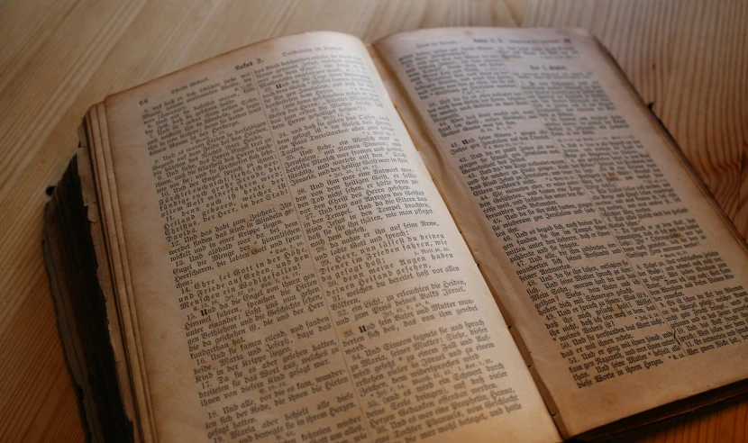 an open book sitting on top of a wooden table, old testament, manufactured in the 1920s, high res photo, unreadable text