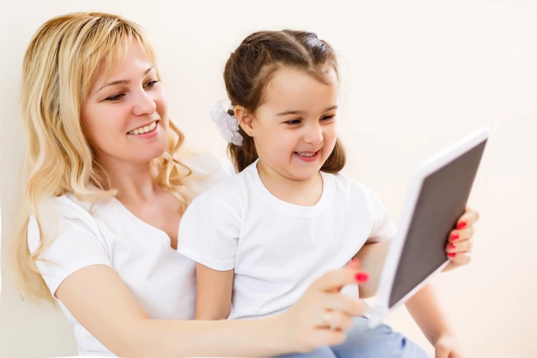 a woman sitting next to a little girl on a bed, a picture, shutterstock, integrating with technology!!, alena, teaching, closeup photo