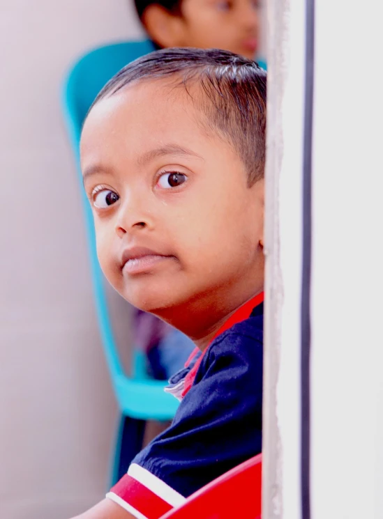 a little boy that is sitting in a chair, hurufiyya, vinayak, with big eyes, leaning on door, face focus!