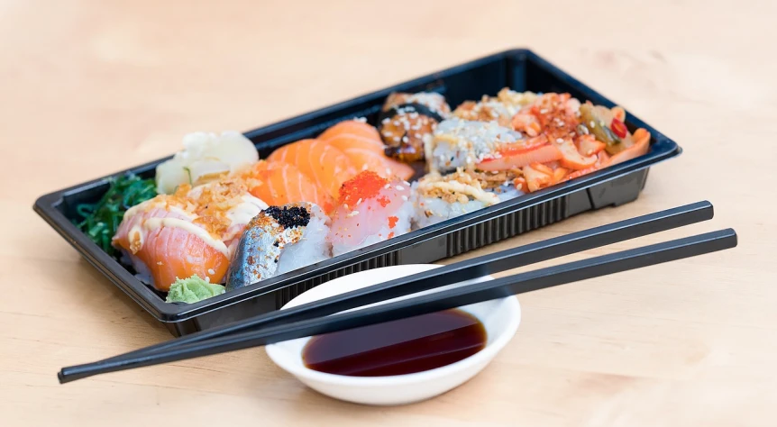 a tray of sushi with chopsticks next to it, a picture, by Adam Manyoki, shutterstock, sōsaku hanga, high detail product photo, 🦩🪐🐞👩🏻🦳, black, crisp colors