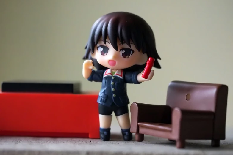 a figurine of a girl holding a cell phone, a picture, by Jin Homura, flickr, girl wearing uniform, on a coffee table, red - cheeks!!, cinematic!!