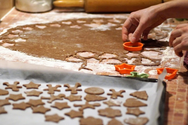 a close up of a person making cookies on a table, by Aleksander Gierymski, gingerbread people, iso: 400, wikimedia commons, crisp clean shapes