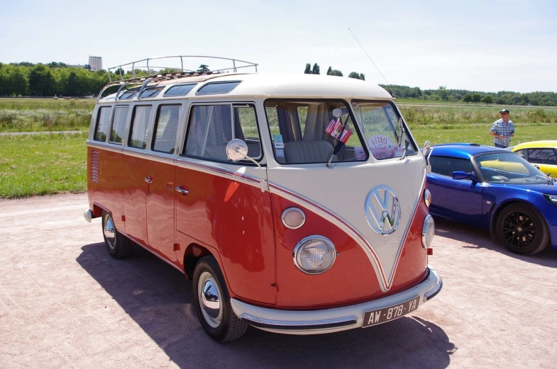 a red and white vw bus parked next to a blue car, shutterstock, retrofuturism, red and brown color scheme, normandy, big windows, wikimedia