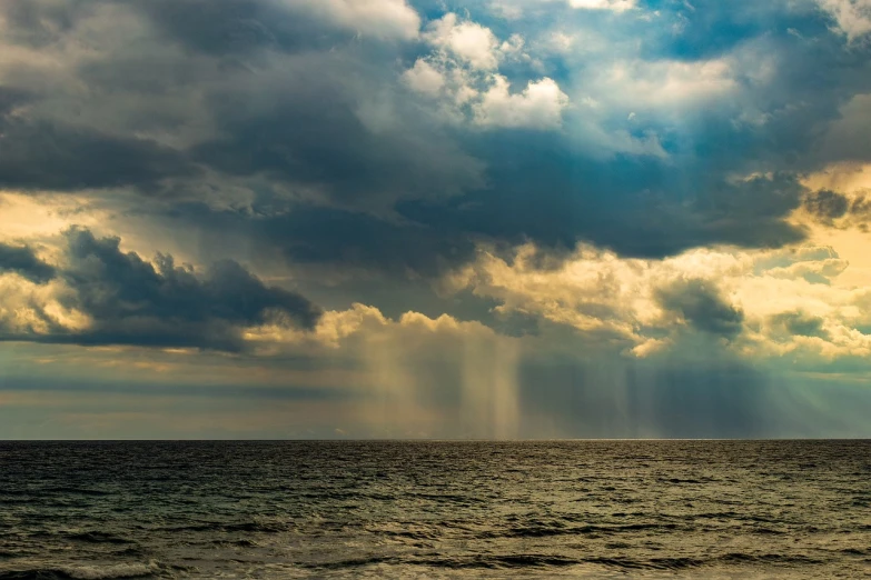 a large body of water under a cloudy sky, a picture, by Ivan Grohar, shutterstock, downpour, black sea, glittering sun rays, mediterranean