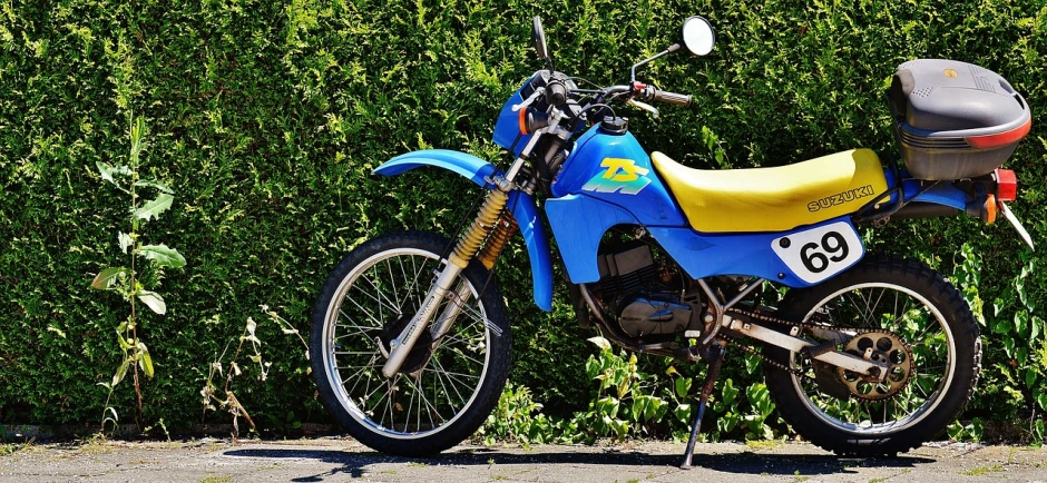 a blue and yellow dirt bike parked in front of a hedge, pixabay, photorealism, 1985 cheverlot k20 c10, close - up profile, swedish style, very crisp details