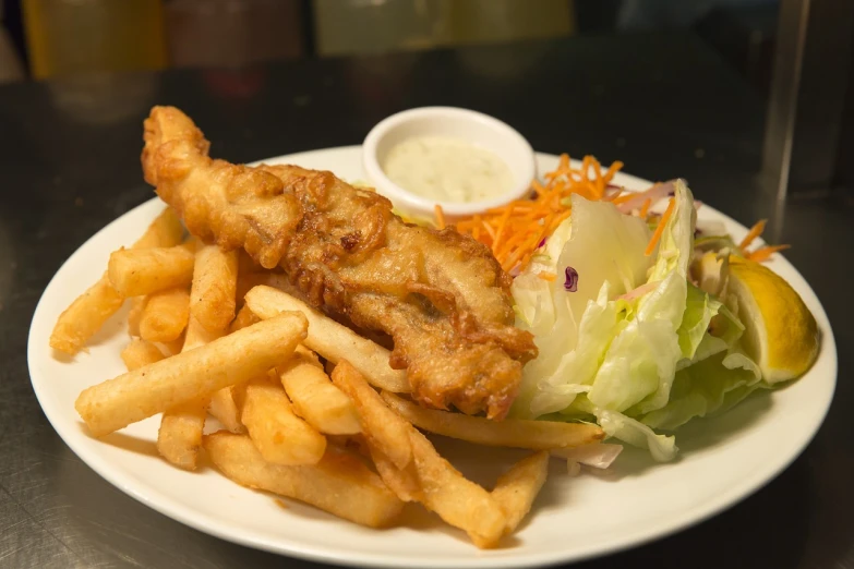a white plate topped with french fries and a salad, pexels, photorealism, fish tail, battered, australian, unedited