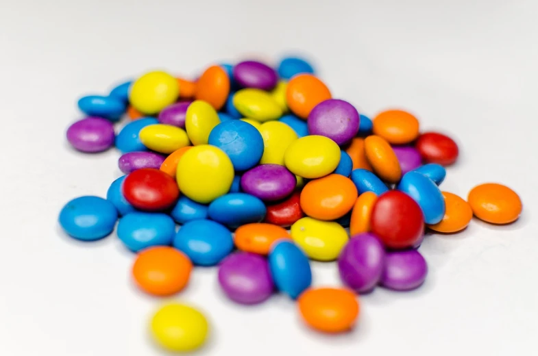 a pile of colorful candy sitting on top of a white table, color field, smooth round shapes, productphoto, close-up product photo, chocolate