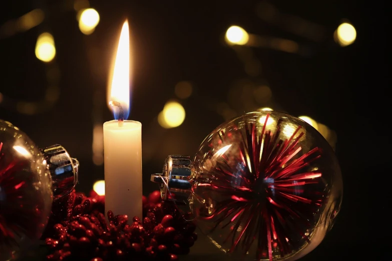 a lit candle sitting next to a christmas ornament, by Bernard D’Andrea, pexels, digital art, video still, candle lightning, its hour come round at last, 💣 💥💣 💥