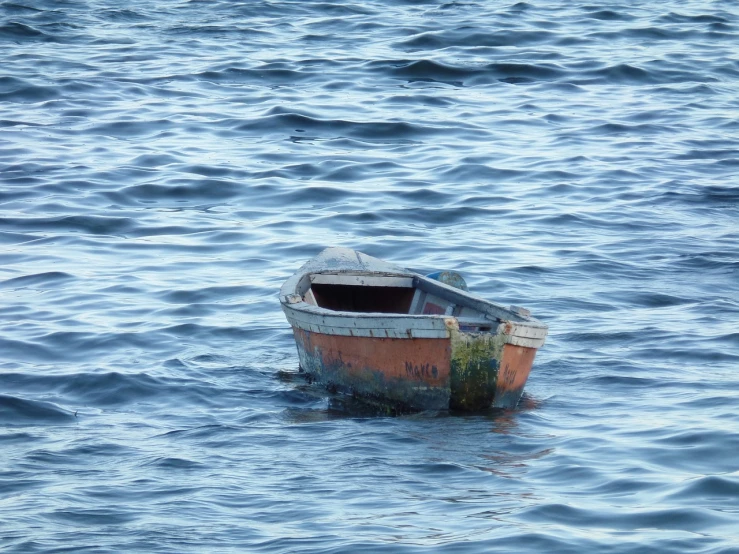 a small boat floating on top of a body of water, a photo, by Richard Carline, shutterstock, weathered, boston, dingy, deep in the ocean