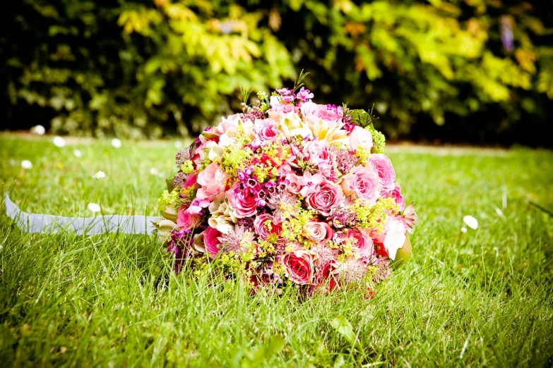 a bouquet of flowers sitting on top of a lush green field, inspired by François Boquet, pexels, romanticism, pink and green, ceremony, very sunny, with a lush grass lawn