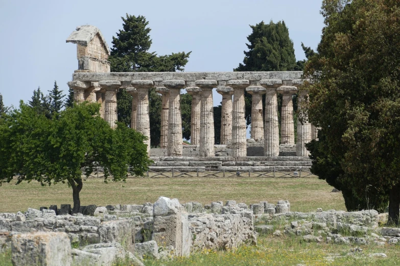 a large stone structure sitting on top of a lush green field, a picture, by Romano Vio, ancient greek temple, former, adorned pillars, featured