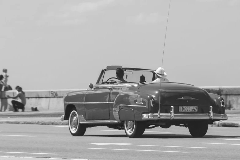 a black and white photo of a classic car, a black and white photo, inspired by Ruth Orkin, pixabay contest winner, cuban revolution, car on highway, soft top, in retro colors